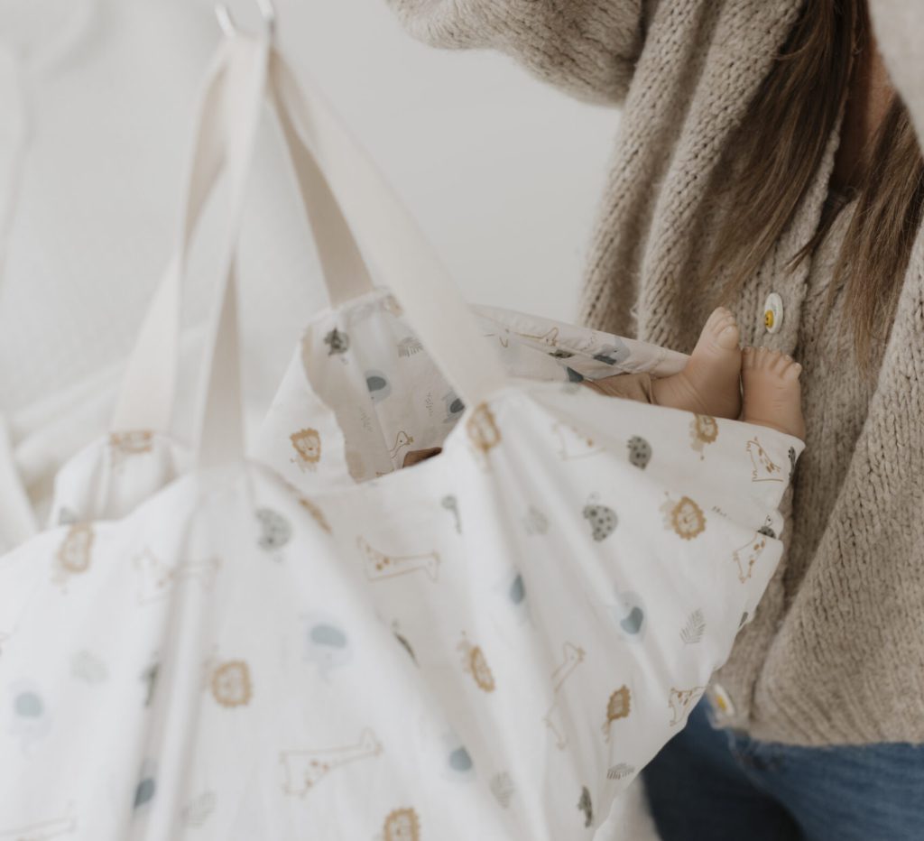 Baby wird in Babywiege gehalten von Hebamme